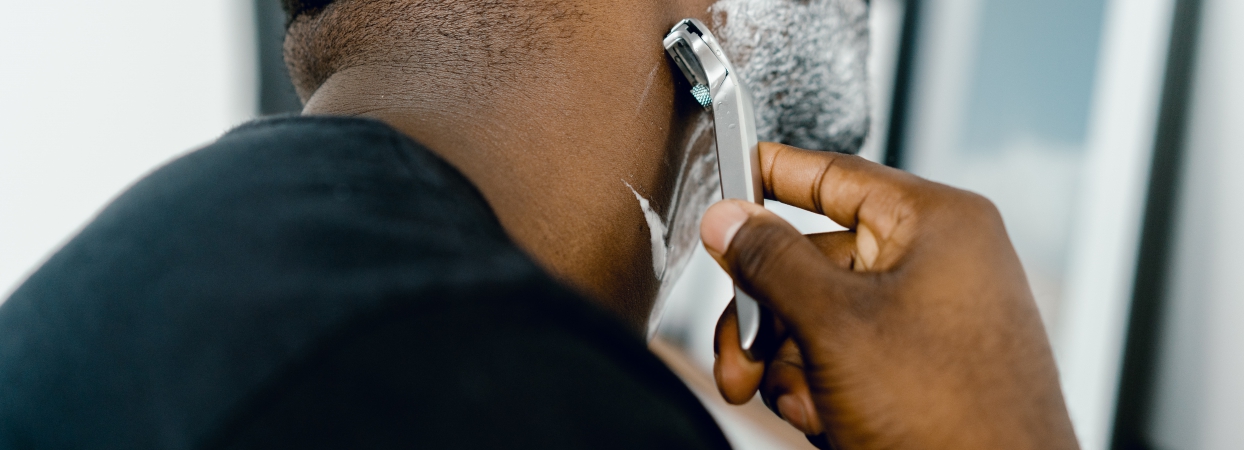 man shaving his beard using grooming products