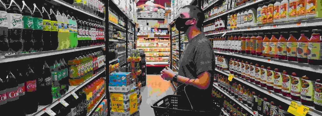 man looking at beverages in a grocery aisle